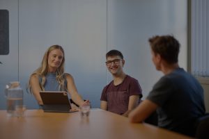 Speech pathologist and young adult with support worker in therapy session